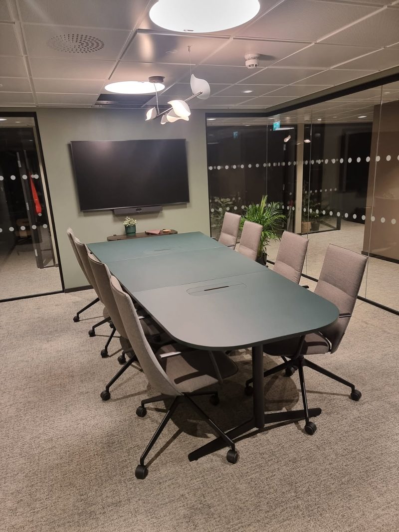 Møterom med langbord, stoler og skjerm på veggen